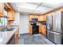 Well-lit kitchen featuring stainless steel appliances, tile flooring, granite counters, and wood cabinetry at 414 Cactus Cir, Seffner, FL 33584