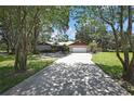 Charming one-story home with a long driveway, stone accents, mature trees, and a well-manicured lawn at 4706 Scott Rd, Lutz, FL 33558