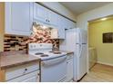 Traditional kitchen featuring white appliances, cabinets and a colorful backsplash design at 5915 Brickleberry Ln # 103, Zephyrhills, FL 33541