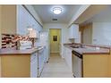 Open kitchen showcases white cabinets, appliances, and laminate flooring plus a window over the sink at 5915 Brickleberry Ln # 103, Zephyrhills, FL 33541