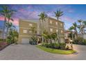 Charming three-story home with a paver driveway, lush landscaping, and multiple palm trees against a beautiful twilight sky at 614 Norton St, Longboat Key, FL 34228