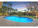 Inviting pool area with surrounding brick pavers, green lawn, and patio dining set with lush tropical landscaping at 614 Norton St, Longboat Key, FL 34228