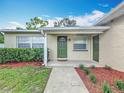 Inviting front porch with a green door, manicured shrubs, and decorative mulch beds at 6521 Cedarbrook S Dr, Pinellas Park, FL 33782
