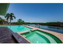 Beautiful pool and spa overlooking the waterway, enhanced by palm trees and lush landscaping at 671 Tallahassee Ne Dr, St Petersburg, FL 33702