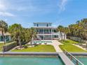 Gorgeous backyard with a swimming pool, lounge chairs, and a private dock on the water at 7115 Bay St, St Pete Beach, FL 33706