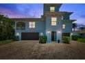 Beautiful blue two-story home with a brick driveway and well manicured landscaping at 7115 Bay St, St Pete Beach, FL 33706