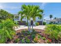Well-manicured front yard featuring palm trees and colorful flowerbeds in front of a light blue home at 7115 Bay St, St Pete Beach, FL 33706