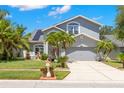 Charming gray two-story home featuring a well-manicured lawn, mature palms, and a two-car garage at 1213 Barmere Ln, Brandon, FL 33511