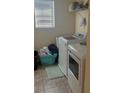 Functional laundry room with full-size washer and dryer, storage shelf, and natural light at 13752 Tensaw Dr, Hudson, FL 34669