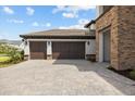 Attached two-car garage with brown doors and a paved driveway at 33750 Ocean Spray Ln, Wesley Chapel, FL 33543