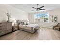 Neutral bedroom with a ceiling fan, light wood floors, large window, and minimalist decor at 3702 W Cass St # 5, Tampa, FL 33609