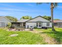Backyard with a screened-in porch, patio set, palm tree and green grass at 8135 Golf Club Ct, Hudson, FL 34667