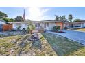 Charming single-story home with a manicured front yard, garden features, and a paved driveway at 8702 Congress St, Port Richey, FL 34668