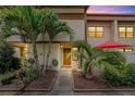 Inviting townhome exterior at dusk with lush tropical landscaping and a charming entryway, enhanced by a red umbrella at 9209 Seminole Blvd # 156, Seminole, FL 33772