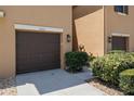 Close up of the townhouse garage with a dark brown door and landscaped front yard and lamp at 9520 Trumpet Vine Loop, Trinity, FL 34655