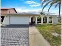 Charming single-Gathering home featuring a two-car garage, decorative archways, and mature palm trees at 9907 Island Harbor Dr, Port Richey, FL 34668