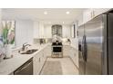 Modern white kitchen featuring stainless steel appliances, granite countertops, and a stylish backsplash at 100 Bluff View Dr # 405A, Belleair Bluffs, FL 33770