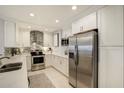 Modern white kitchen featuring stainless steel appliances, granite countertops, and a stylish backsplash at 100 Bluff View Dr # 405A, Belleair Bluffs, FL 33770