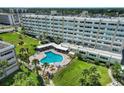 Aerial view of the community pool surrounded by lush landscaping, and the condominium building at 100 Bluff View Dr # 405A, Belleair Bluffs, FL 33770