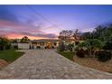 Beautifully landscaped home exterior with a long, patterned brick driveway at sunset at 106 Midway Is, Clearwater Beach, FL 33767