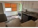 Dated kitchen with linoleum floors, white cabinetry and a window letting in natural light at 1118 E Linebaugh Ave, Tampa, FL 33612