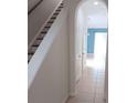 Hallway with tile flooring leading to living area, featuring archway and staircase with white and brown colors at 1508 Talisker Dr, Clearwater, FL 33755