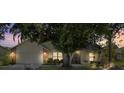 Exterior home facade at dusk featuring mature shade trees, brick accents, warm lighting and neutral color palette at 1914 Elk Spring Dr, Brandon, FL 33511