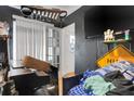 Untidy bedroom with dark walls, blinds, and an assortment of personal belongings, featuring a mounted flat-screen television at 3008 Jackson N St, St Petersburg, FL 33704