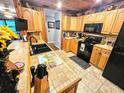 Cozy kitchen featuring wood cabinets, black appliances, tile countertops and flooring at 35031 Shale St, Webster, FL 33597