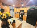 Cozy kitchen featuring wood cabinets, black appliances, tile countertops and flooring at 35031 Shale St, Webster, FL 33597
