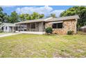 Single-story home with stone exterior details and a screened porch, complemented by lush surrounding trees at 4312 Las Vegas Dr, New Port Richey, FL 34653