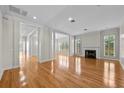 Bright living room featuring hardwood floors, a fireplace, and large windows with shutters for abundant natural light at 4518 W Woodmere Rd, Tampa, FL 33609
