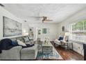 Bright living room with hardwood floors, a ceiling fan, a comfortable gray couch, and stylish decor throughout at 670 Wooddell Dr, Safety Harbor, FL 34695