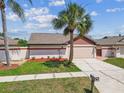 Inviting single-story home showcasing a verdant lawn and a sealed driveway, enhanced by mature trees at 7004 Westminster St, Tampa, FL 33635