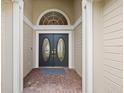 Elegant double front doors with decorative glass inserts, enhanced by an arched window and brick flooring at 9084 Quail Creek Dr, Tampa, FL 33647
