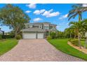 Inviting two-story home with a brick driveway, lush landscaping, and a three-car garage at 1171 Red Maple Ne Cir, St Petersburg, FL 33703