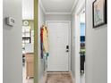 Hallway with tile floors leads to white front door, with view of the kitchen and an adjacent office at 12648 Castle Hill Dr, Tampa, FL 33624