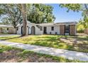 Inviting single-story house with green lawn, mature trees, and a brick accent wall at 1708 Julian Lane Dr, Tampa, FL 33619