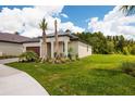 Beautifully landscaped front yard with lush green grass, palm trees, and meticulous plantings showcasing curb appeal at 17263 Mango Shay Ct, Land O Lakes, FL 34638
