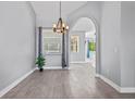 Open dining room with wood-look tile flooring, chandelier and arched entryway at 2498 Saddlewood Ln, Palm Harbor, FL 34685
