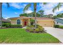 Inviting single-story home featuring a well-manicured lawn and a bright red front door at 2498 Saddlewood Ln, Palm Harbor, FL 34685