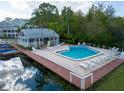 A beautiful in-ground pool is surrounded by lounge chairs and a nearby recreation building with a metal roof at 2533 Dolly Bay Dr # 203, Palm Harbor, FL 34684