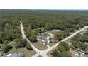 An aerial view showcases the home nestled on a lot surrounded by lush trees, close to a road, and a short distance from town at 27709 Robin Roost Ln, Wesley Chapel, FL 33544
