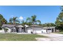Charming home featuring a two-car garage, large front yard, palm trees, and modern exterior paint at 27709 Robin Roost Ln, Wesley Chapel, FL 33544