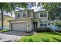 Two story home showcasing a well-manicured lawn, neutral color scheme, attached two car garage and trimmed windows at 3002 Savannah Oaks Cir, Tarpon Springs, FL 34688