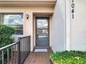 Close-up of the front door entrance, with tiled porch and freshly trimmed greenery at 1041 Bowsprit Ln # 1041, Holiday, FL 34691
