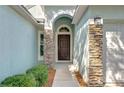 Close-up of the front entrance showcasing a brown door with stone pillars and manicured bushes at 11567 Weston Course Loop, Riverview, FL 33579