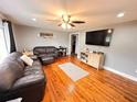 Cozy living room featuring hardwood floors, a ceiling fan, and a comfortable leather sofa set at 1233 Belleair Rd, Clearwater, FL 33756