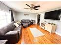 Cozy living room featuring hardwood floors, a ceiling fan, and a comfortable leather sofa set at 1233 Belleair Rd, Clearwater, FL 33756