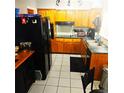 Charming kitchen with wood cabinetry, black appliances, and tile flooring at 1663 Cambridge Dr, Clearwater, FL 33756